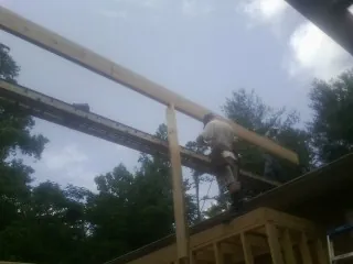 Carpenter setting a ridge beam over a new addition frame — Ice Dam Removal by Roofing Brothers in Hammett