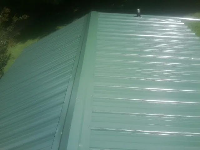New green metal panels meeting at the ridge of a roof — Flat Roof Repair work by our crew in Hammett