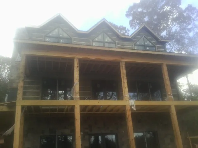 Dormers and porch framing on a large log home under construction — Roof Coating work by our crew in Hammett