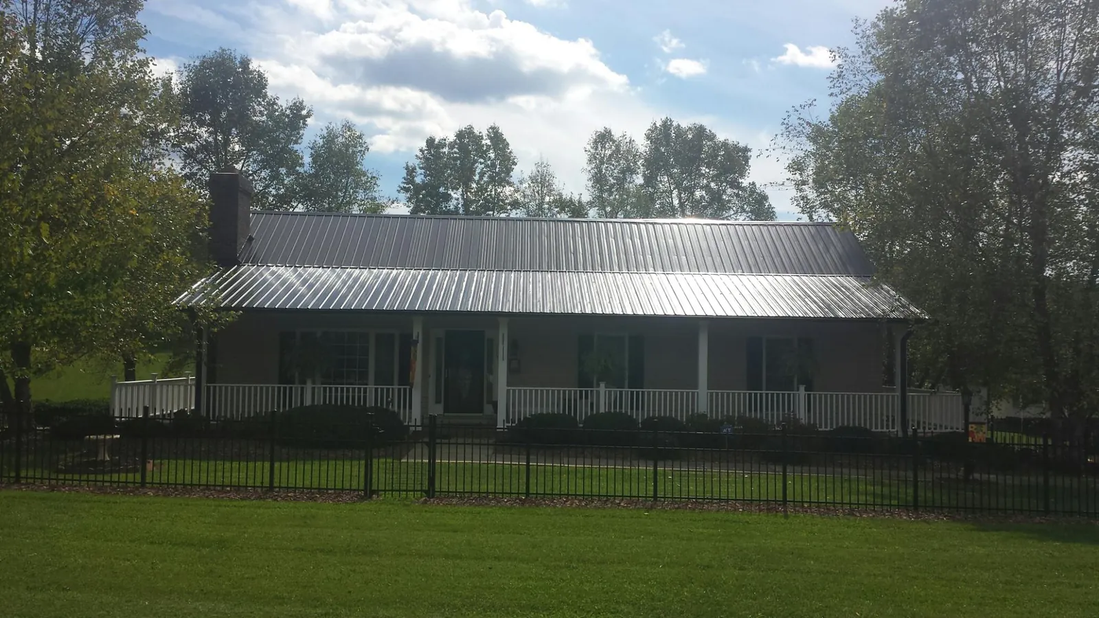 Gray metal roof on a brick ranch with a full width front porch — Gutter Guard Installation work by our crew in Hammett
