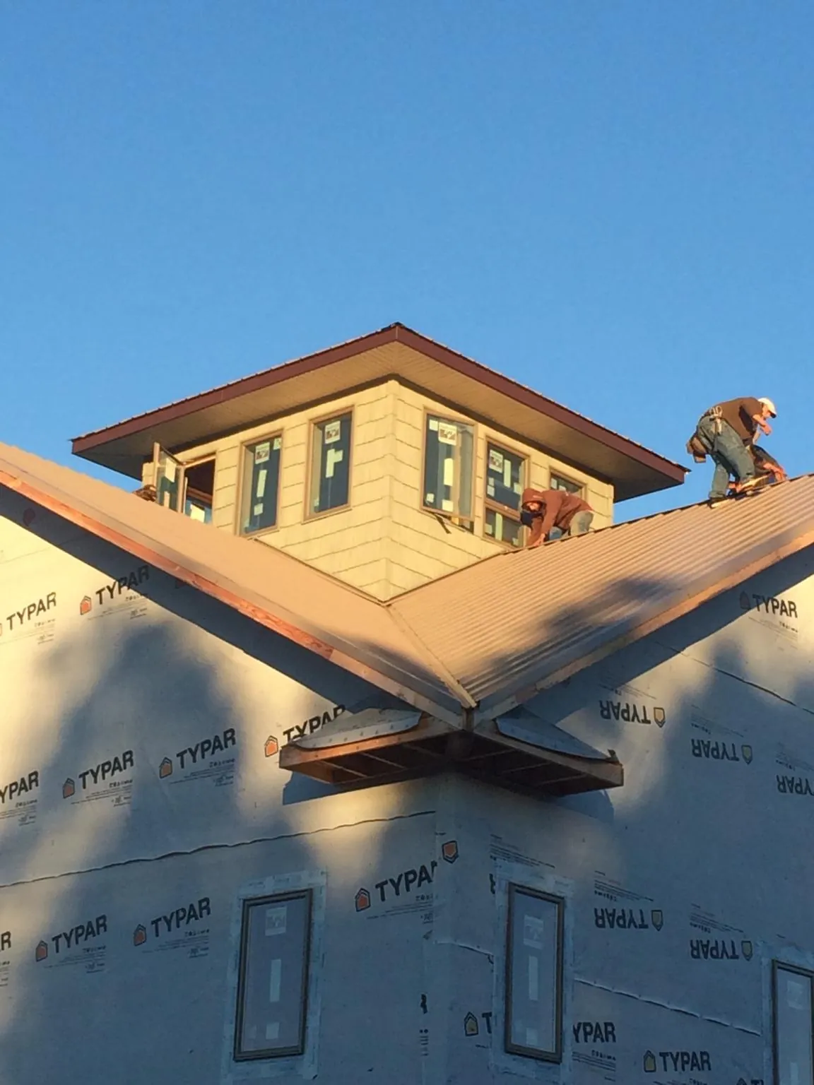 Roofers working around a rooftop cupola on a new metal roof at sunset — Roof Waterproofing in Hammett by Roofing Brothers